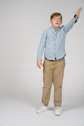 Vista frontal de un niño apuntando hacia arriba con la mano