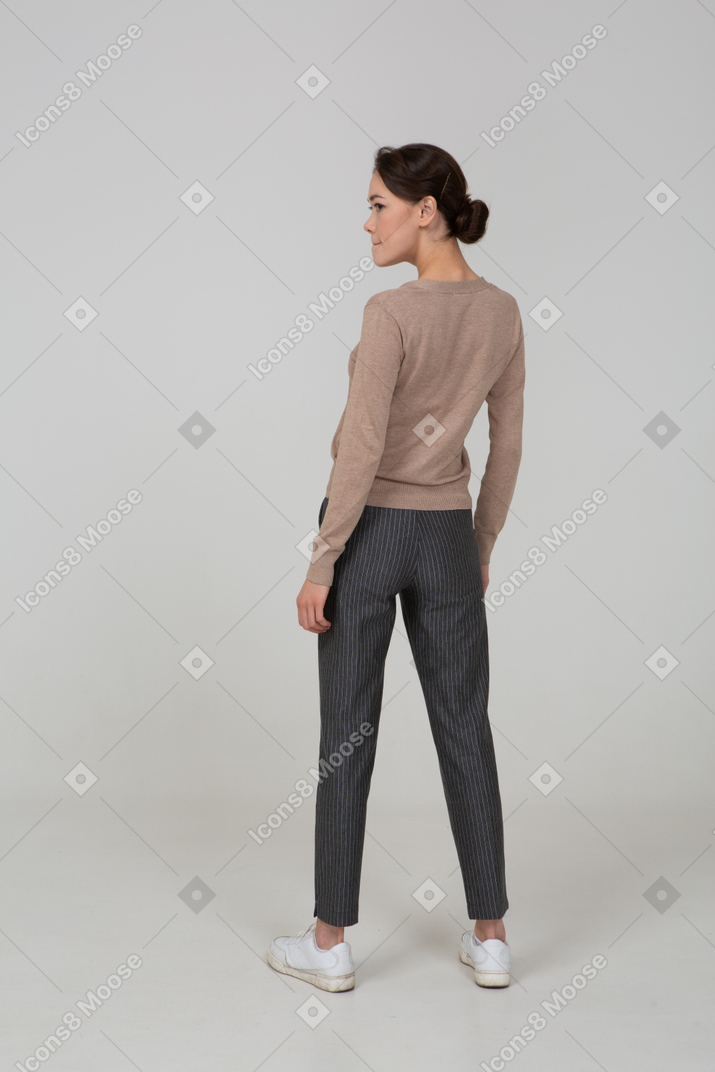 Three-quarter back view of a displeased female in pullover and pants pressing lips