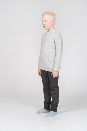 Three-quarters view of a kid boy in casual clothes looking surprisingly