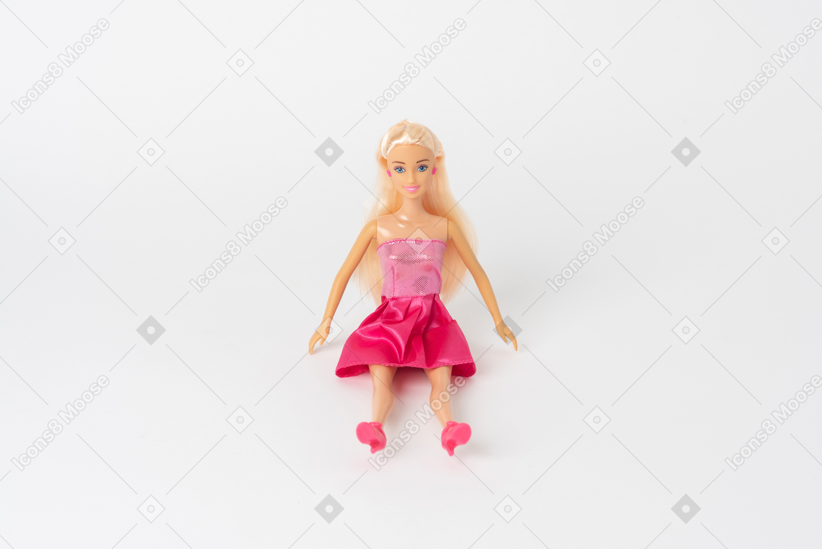 Uma linda boneca barbie em um vestido rosa brilhante e salto alto rosa sentado isolado contra um fundo branco liso