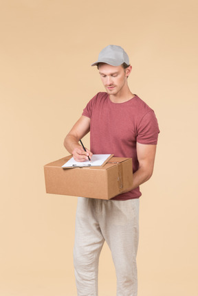 Delivery guy holding box and writing something down in the folder