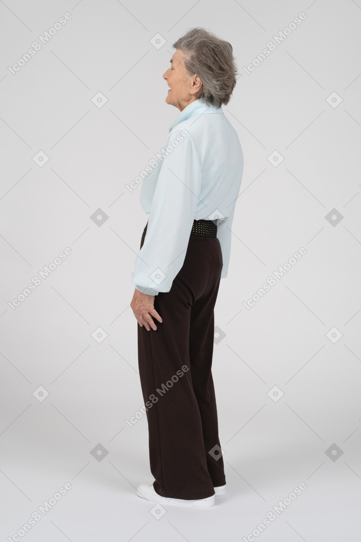 Вид сзади на смеющуюся пожилую женщину в три четверти