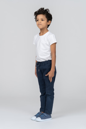 A boy standing with hands alongside body