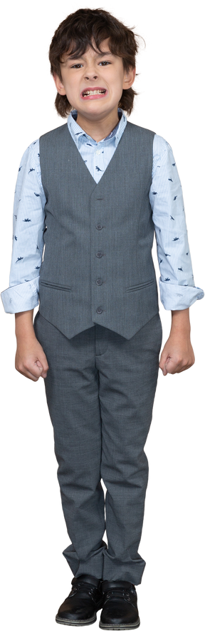 くいしばられた握りこぶしで立っている灰色のスーツを着た怒っている少年の正面図