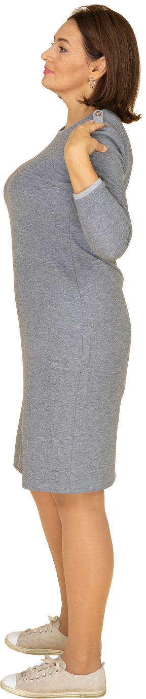 Vista laterale di una donna in abito grigio in piedi con le mani sulle spalle