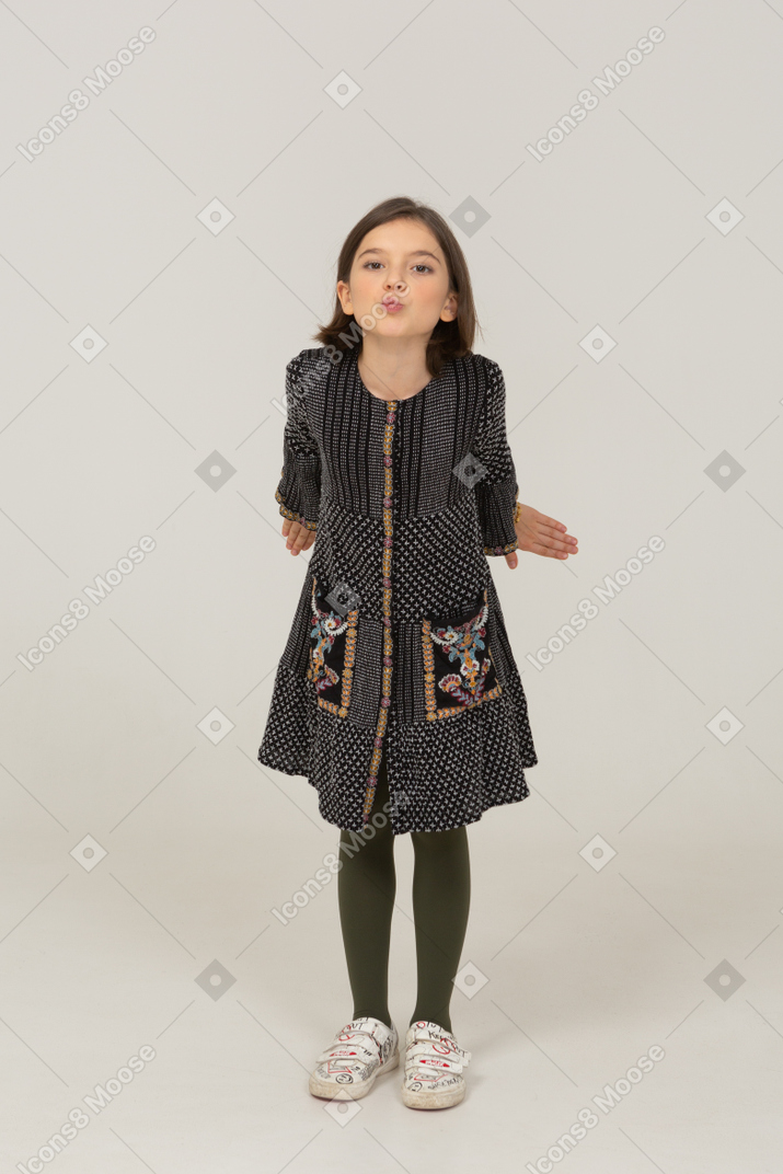 Front view of a little girl in dress outspreading hands and leaning forward