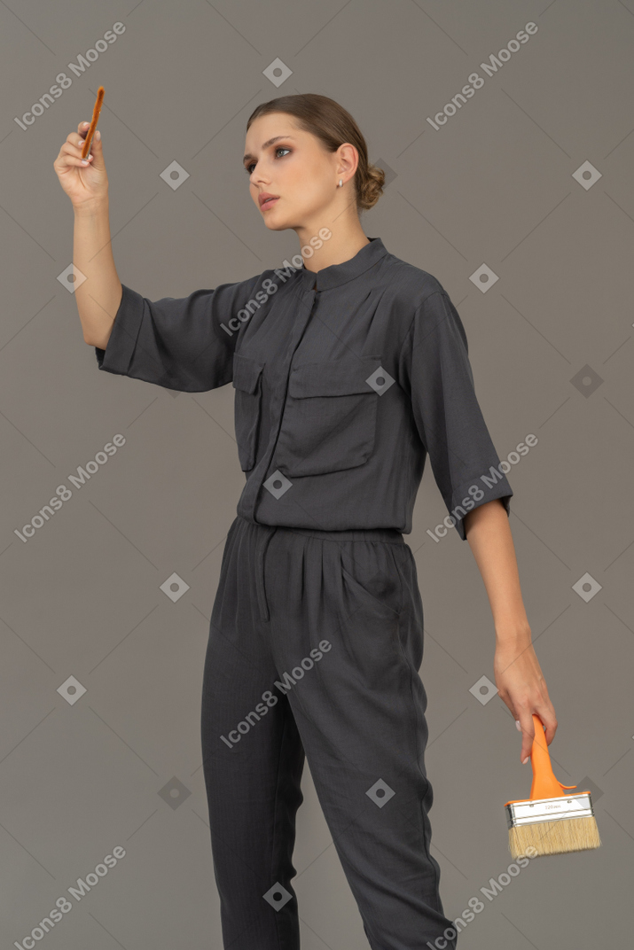 Frau in grauen overalls posiert mit pinseln