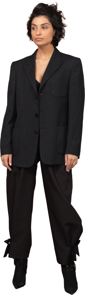 Vista frontal de uma empresária descontente em um terno preto olhando para o lado