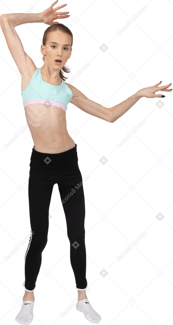 Vista frontal de uma adolescente em roupas esportivas, levantando as mãos e abrindo a boca