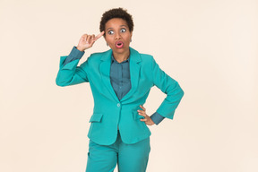 Black woman with a short haircut, wearing all blue, standing against a plain pastel background, looking emotional