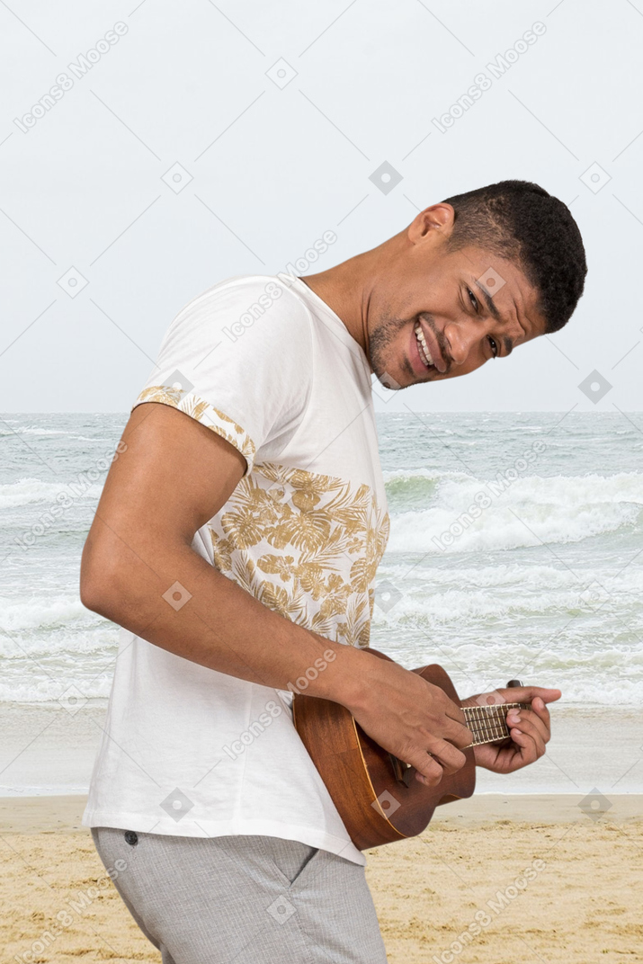 A man playing a ukulele on the beach