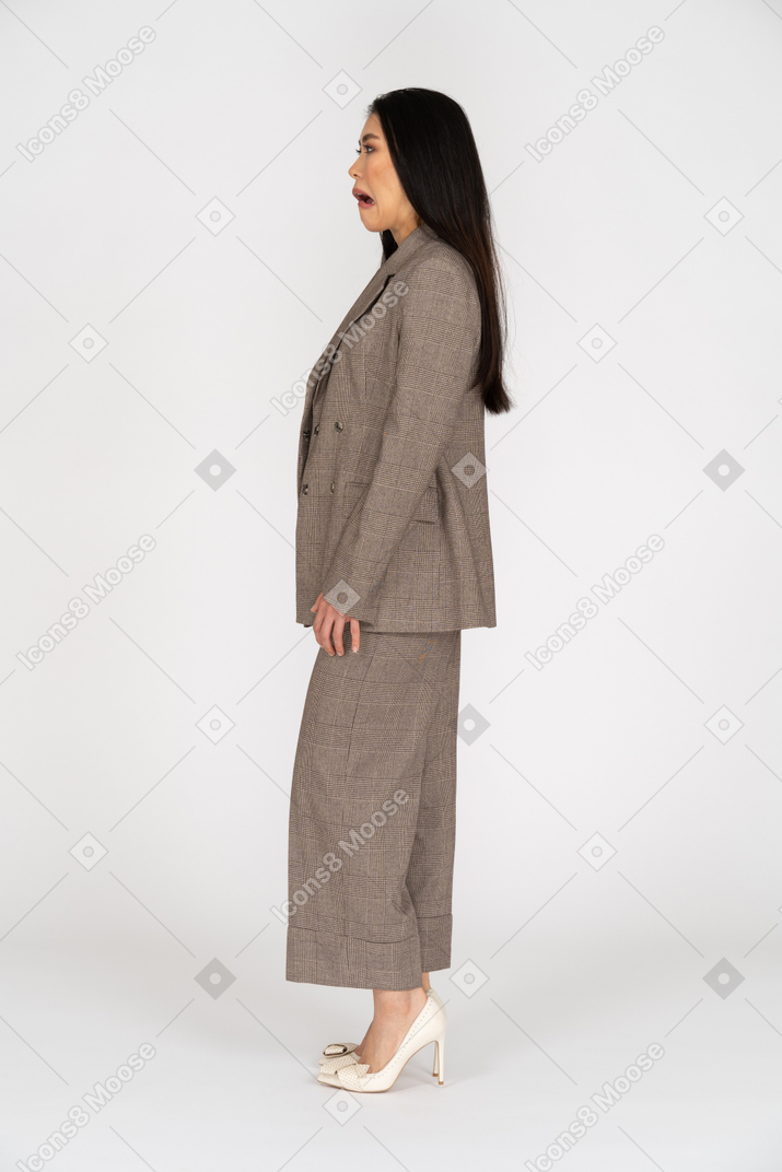 Side view of a grimacing young lady in brown business suit looking aside