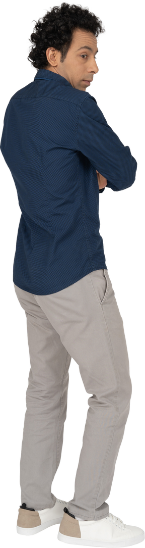 Vista lateral de um homem com roupas casuais posando com os braços cruzados