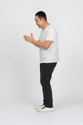 Side view of a cheerful man in casual clothes rubbing hands