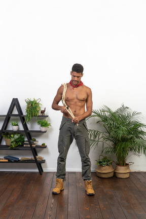 Front view of muscular young man cutting rope with a knife