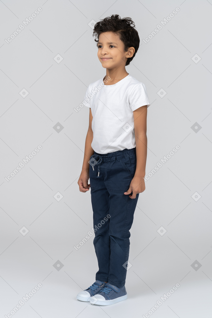 A boy standing with hands alongside body