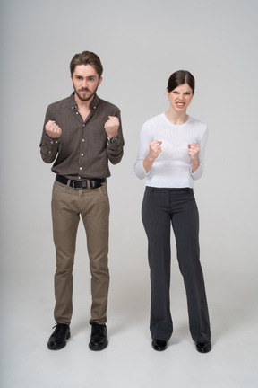 Front view of a furious couple in office clothing clenching fists