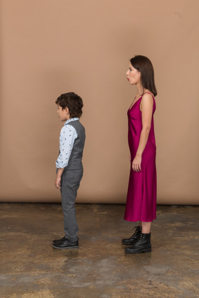 Boy and woman in red dress standing in profile