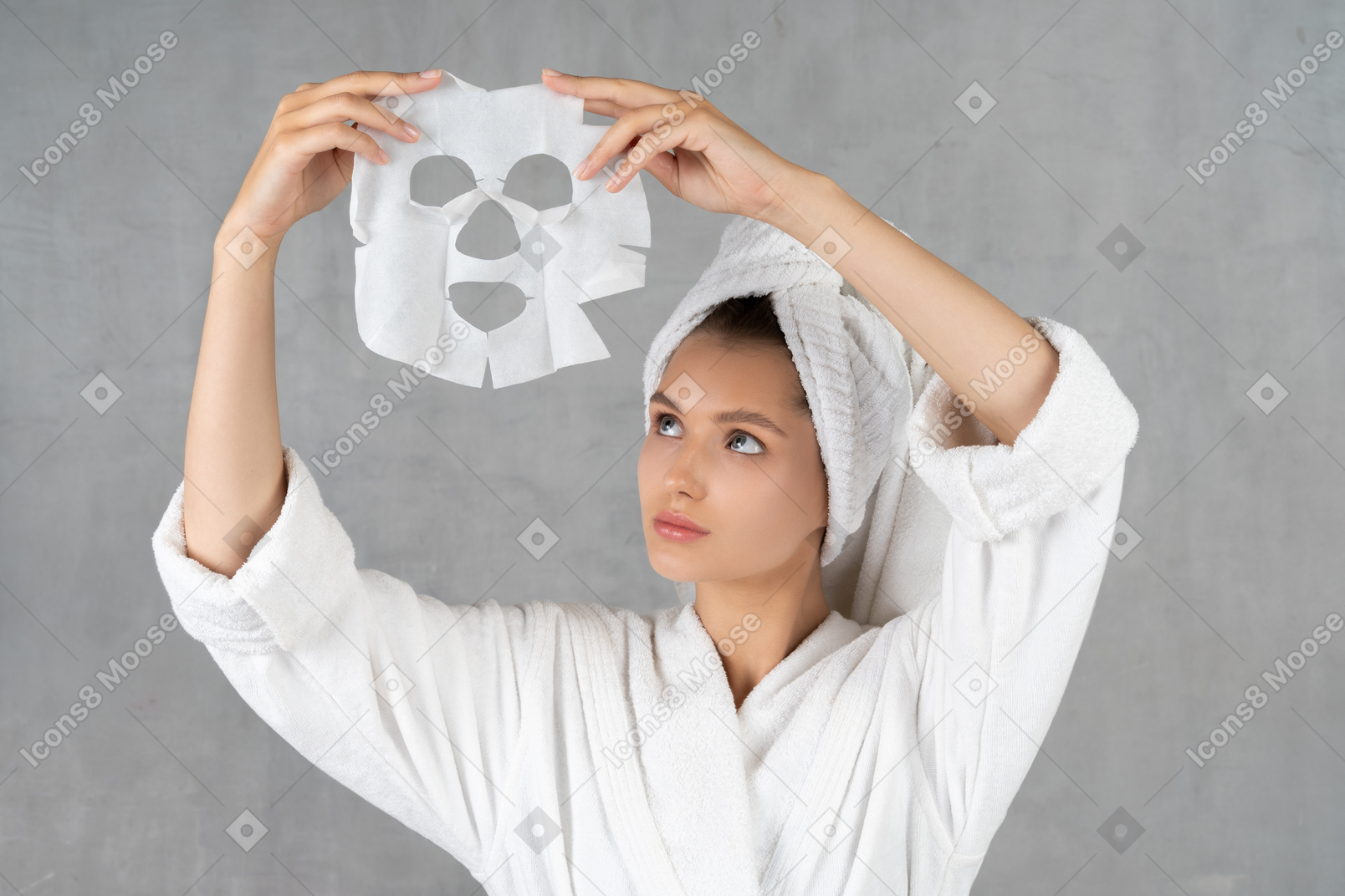 Woman in bathrobe holding up a sheet mask