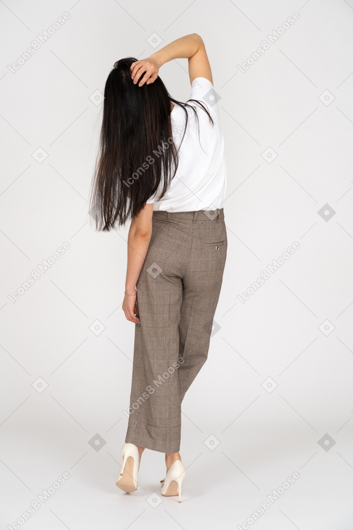 Vista posteriore di una giovane donna in calzoni toccando la testa