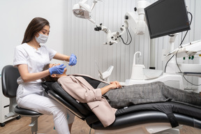 Longitud total de una dentista examinando a su paciente acostada en un gabinete de hospital