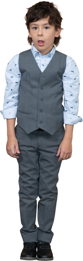 Vista frontale di un ragazzo carino in abito grigio in piedi con la bocca aperta