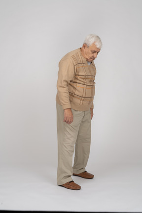 Vue latérale d'un vieil homme triste dans des vêtements décontractés regardant vers le bas