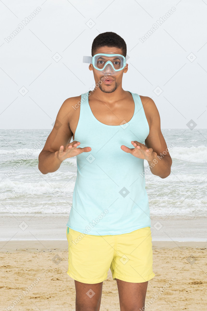 A man standing on a beach wearing goggles