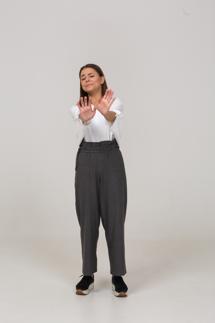 Front view of an unwilling young lady in office clothing outstretching arm