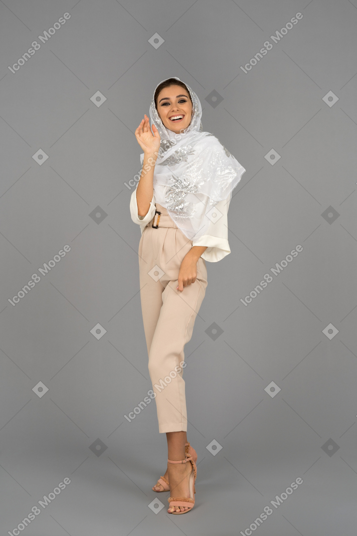 Cheerful young arab woman laughing and waving with a hand