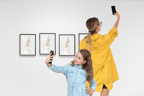 Woman and girl taking selfies in an art gallery