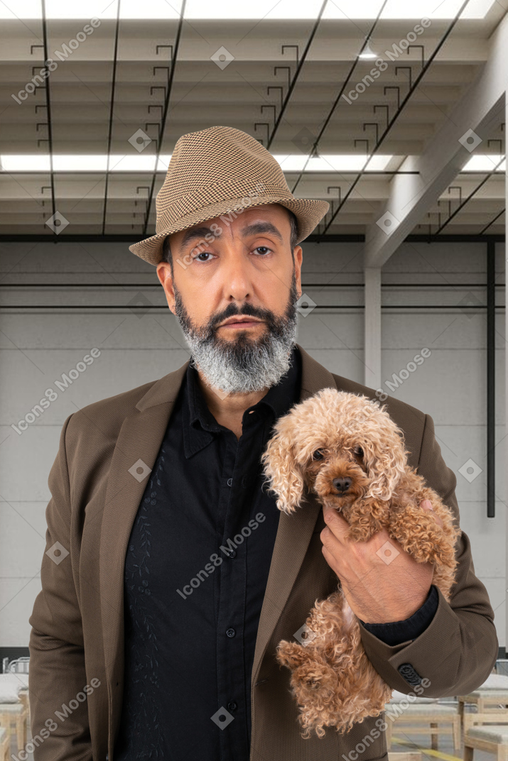 Красивый зрелый человек держит свою собаку на руках