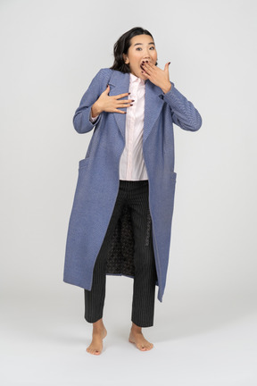 Surprised woman in coat covering her mouth