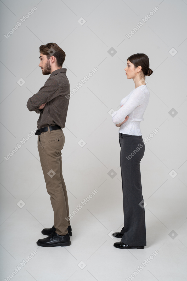 Vista laterale di una giovane coppia in abiti da ufficio che incrociano le braccia