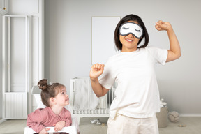 A woman in a sleep mask standing next to a little girl