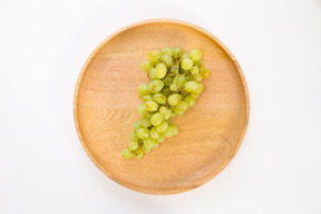 Branch of white grapes on wooden plate