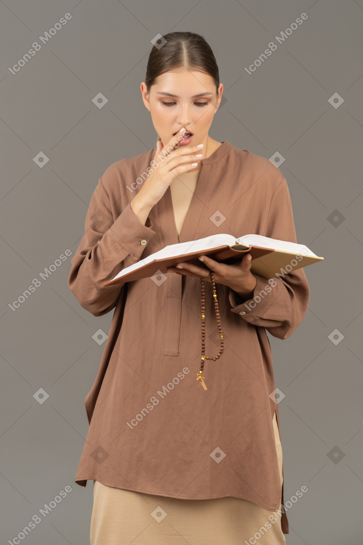 Woman reading a book while touching her lips
