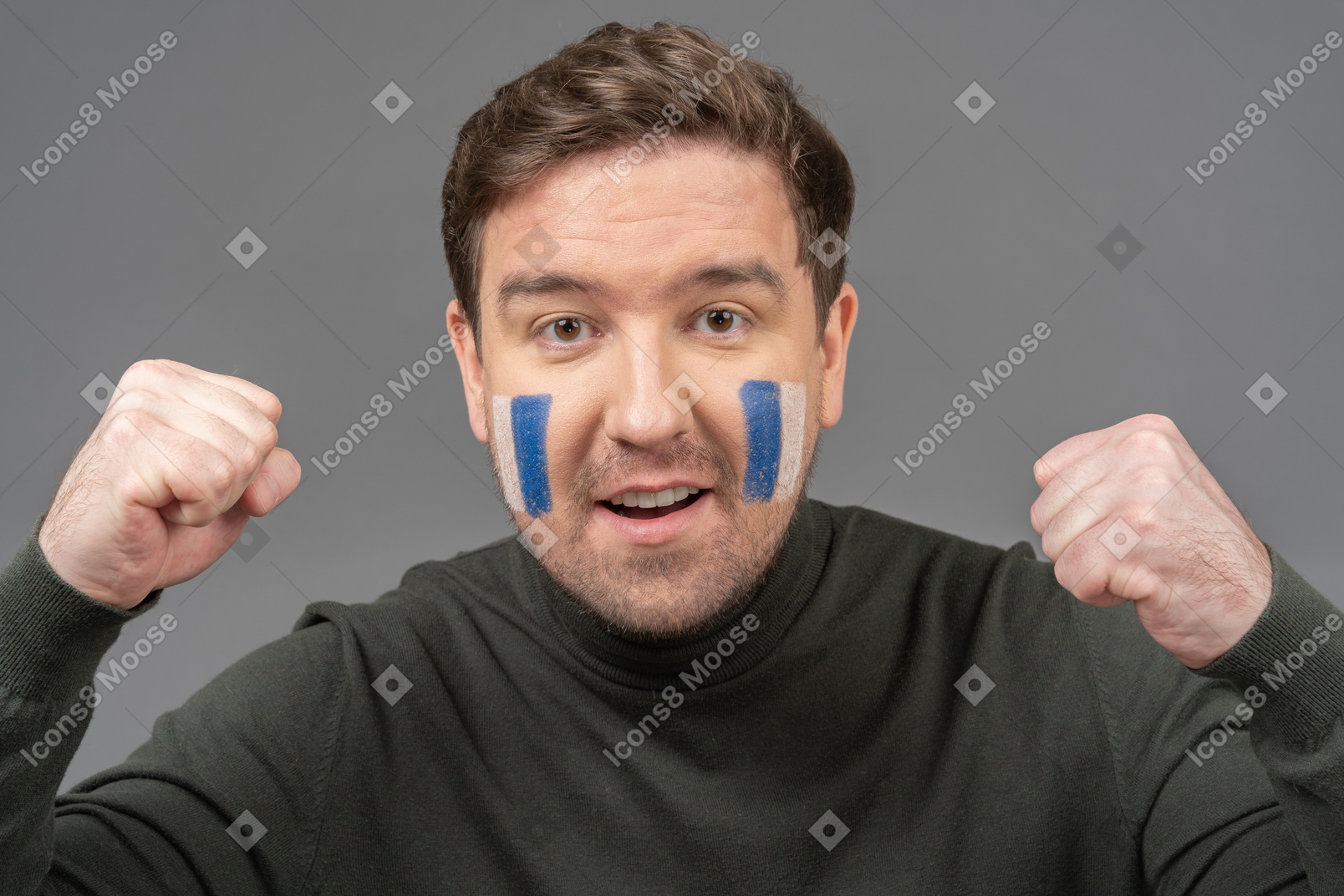 Front view of a male football fan with blue & white face art clenching fist