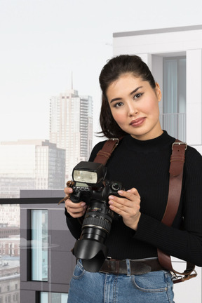 A woman is holding a camera and posing for a picture