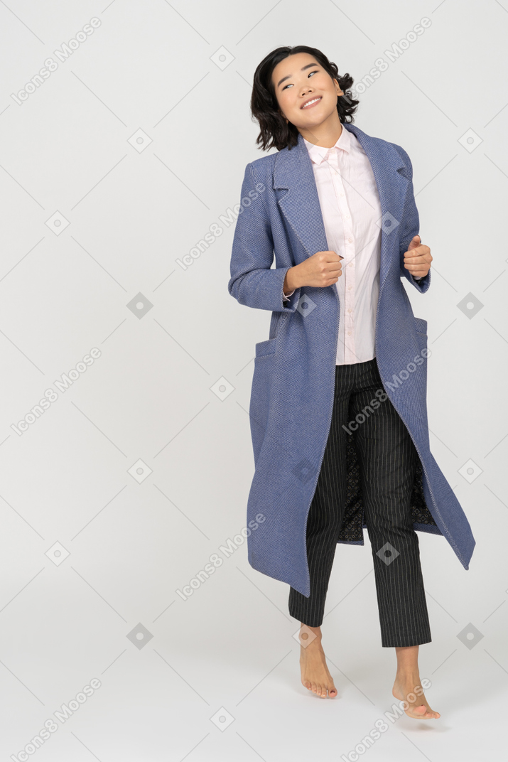Mujer sonriente con abrigo corriendo descalza