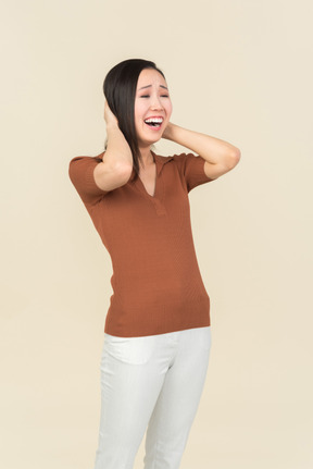 Laughing young asian woman holding hands behind the head