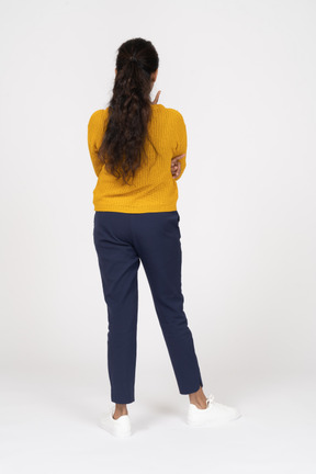 Back view of a girl in casual clothes pointing up with a finger