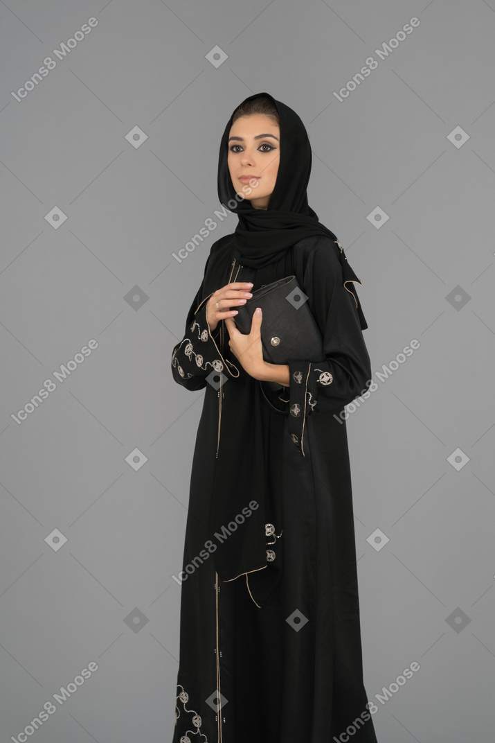 ハンドバッグを保持している若いイスラム教徒の女性