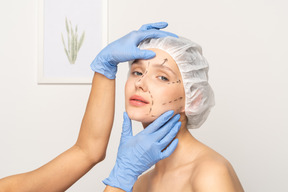 Mujer joven con marcas faciales preparándose para la cirugía