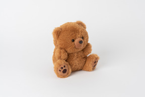 Un mignon petit ours en peluche brun assis isolé sur un fond blanc uni