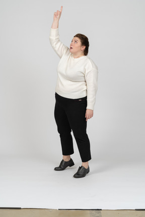 Front view of a plus size woman in casual clothes standing with raised arm