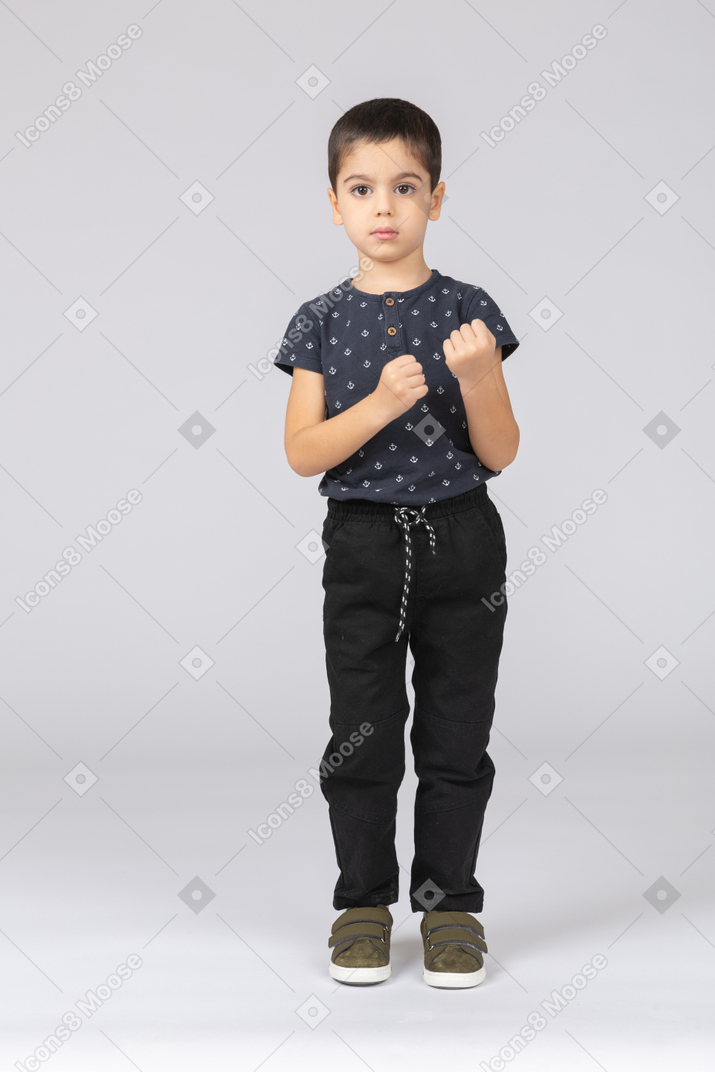 Vista frontal de um garoto sério olhando para a câmera e mostrando os punhos