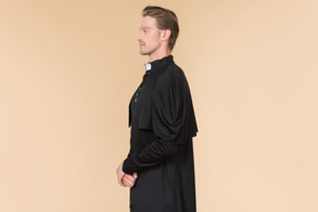 Catholic priest in cassock standing in profile