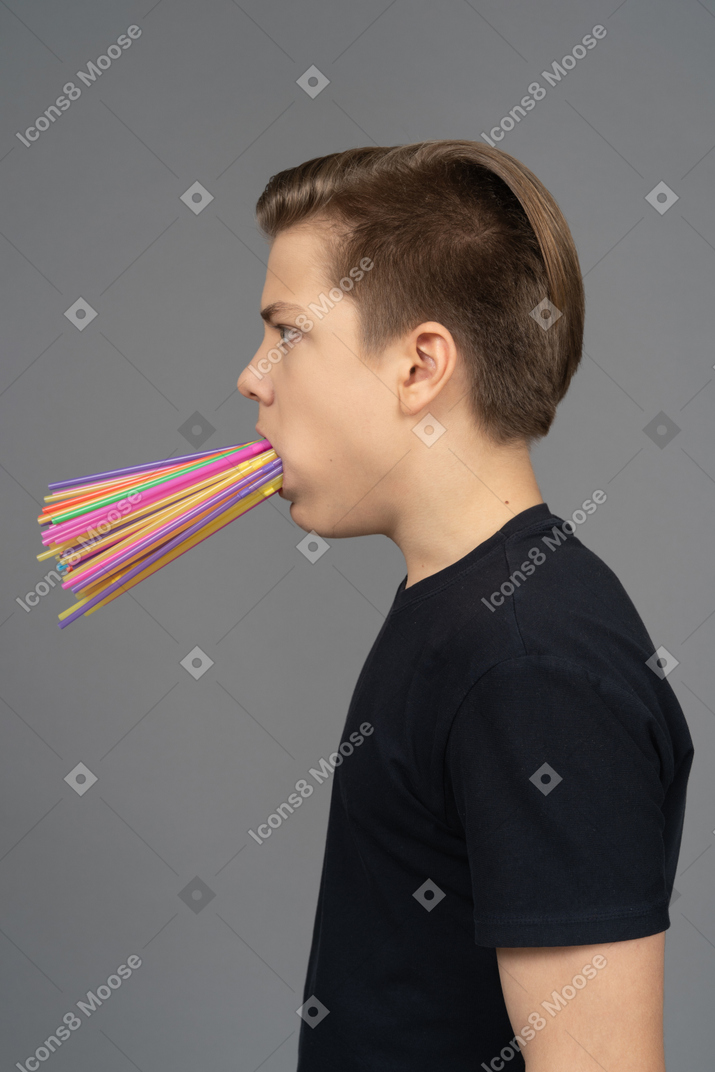 Seitenporträt des jungen mannes, der plastikstrohhalme in seinem mund hält