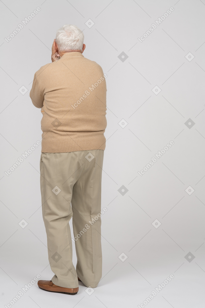 Rear view of an old man covering face with hands